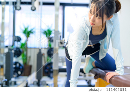 パーソナルジムで体を鍛える若い女性　ワンハンドローイング　ダンベルロウ　筋トレ女子　 111403051