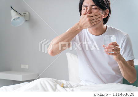 寝室で内服薬・サプリ・医薬品を飲む病気の男性・投薬 寝室で内服薬・サプリ・医薬品を飲む病気の男性・投薬 111403629