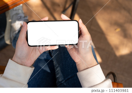 A woman watching videos on her smartphone while relaxing on a bench outdoors. A woman watching videos on her smartphone while relaxing on a bench outdoors. 111403981