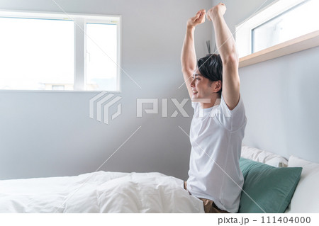 寝室で良質な睡眠・熟睡・快眠して起きる男性(ストレッチ・伸び・朝日) 寝室で良質な睡眠・熟睡・快眠して起きる男性(ストレッチ・伸び・朝日) 111404000