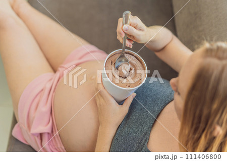 Happy pregnant young woman eating ice cream Happy pregnant young woman eating ice cream 111406800