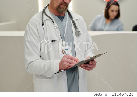Male clinician making medical notes Male clinician making medical notes 111407020
