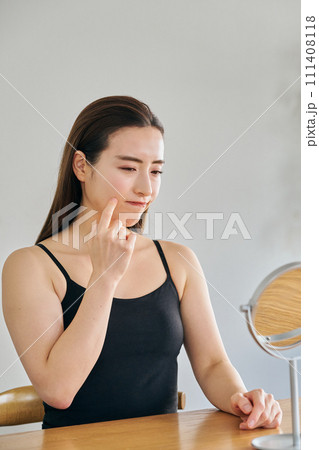鏡を見ながら肌のシワを気にする30代女性 111408118