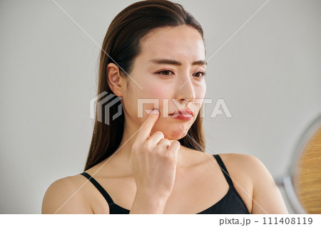 鏡を見ながら肌のシワを気にする30代女性 鏡を見ながら肌のシワを気にする30代女性 111408119