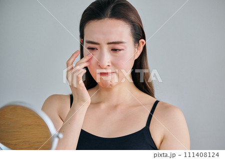 鏡を見ながら目元のシワを気にする30代女性 111408124
