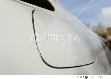 Closeup Scratch On Cap Of Filler Neck, Gas Tank Of White Car. Paint Or Polishing The Clear Coat With A Rubbing Compound. Car Dent Repair. Blue Sky On Background Closeup Scratch On Cap Of Filler Neck, Gas Tank Of White Car. Paint Or Polishing The Clear Coat With A Rubbing Compound. Car Dent Repair. Blue Sky On Background 111408899