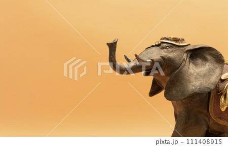 Design World Elephant Day. Bronze Decorated Elephant On Peach Yellow Background. Copy Space, Postcard. Ganesha Chaturthi Holiday. Sacred Symbol In Hindu And Buddhist Religions. Design, Horizontal 111408915