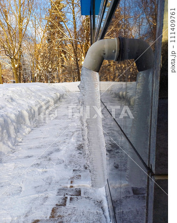 Drain pipe with frozen stream of water outdoors. 111409761