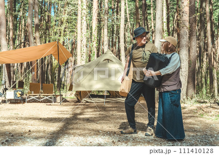 キャンプ場で寝袋を持って荷物を運ぶアジア人の夫婦キャンパー(グランピング・林間サイト) キャンプ場で寝袋を持って荷物を運ぶアジア人の夫婦キャンパー(グランピング・林間サイト) 111410128