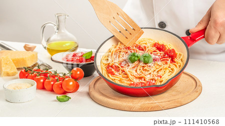 Italian pasta with tomatoes and basil in pan. Chef cooking spaghetti Italian pasta with tomatoes and basil in pan. Chef cooking spaghetti 111410568