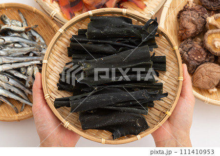 根昆布と煮干しと干し椎茸と厚削りの鰹節を持つ女性の手元 根昆布と煮干しと干し椎茸と厚削りの鰹節を持つ女性の手元 111410953