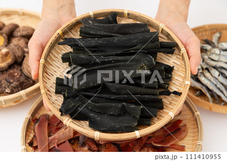 根昆布と煮干しと干し椎茸と厚削りの鰹節を持つ女性の手元 根昆布と煮干しと干し椎茸と厚削りの鰹節を持つ女性の手元 111410955