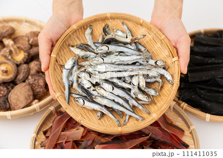 根昆布と煮干しと干し椎茸と厚削りの鰹節を持つ女性の手元 根昆布と煮干しと干し椎茸と厚削りの鰹節を持つ女性の手元 111411035