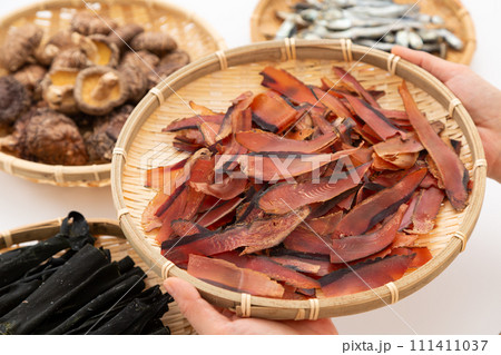 根昆布と煮干しと干し椎茸と厚削りの鰹節を持つ女性の手元 根昆布と煮干しと干し椎茸と厚削りの鰹節を持つ女性の手元 111411037