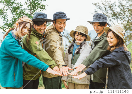 秋冬のキャンプ場で仲間と一致団結して円陣を組む男女（友情・友達・チームワーク・アウトドア） 111411146
