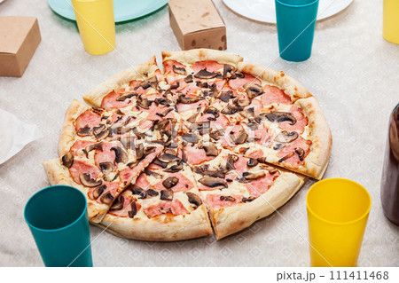 close-up of italian pizza with sausage and mushrooms on the festive table during a party close-up of italian pizza with sausage and mushrooms on the festive table during a party 111411468
