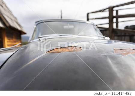 Car paint stripping decay. Peeling paint and rusted metal on an old timer vehicle 111414483