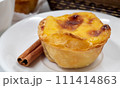 Plate with one Portuguese Pastel de Nata pie with custard and cinnamon sticks. Pastel de Belem is an iconic cup-shaped pastry with a burnt top and a crispy puff pastry crust. Sweet dessert 111414863
