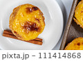 Pastel de nata tarts or Portuguese egg tart and cinnamon sticks isolated on white background. Pastel de Belem is a small pie with a crispy puff pastry crust and a custard cream filling 111414868