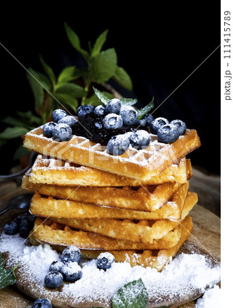 Waffles with fresh blueberries and powdered sugar on the rustic table. Freshly made Belgian waffles 111415789