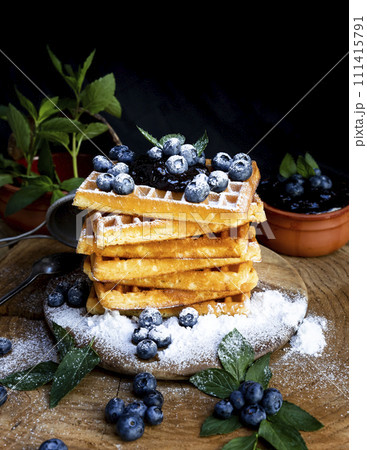 Waffles with fresh blueberries and powdered sugar on the rustic table. Freshly made Belgian waffles 111415791