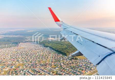 View of airplane wing, blue skies and green land during landing. Airplane window view. 111415845