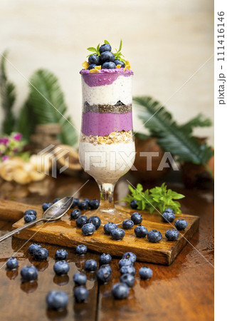 Blueberry smoothies with chia seeds in glass with fresh berries and mint on wooden table 111416146
