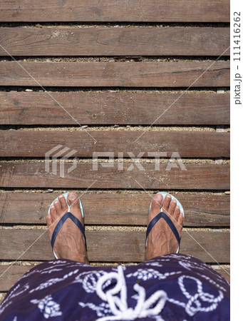 Mans feet in flip flops on wooden boardwalk. Top view. Flat lay. Empty space, for text 111416262