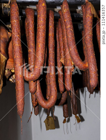 Smoked, dry, cured sausages hanging in an old smokehouse Smoked, dry, cured sausages hanging in an old smokehouse 111416357
