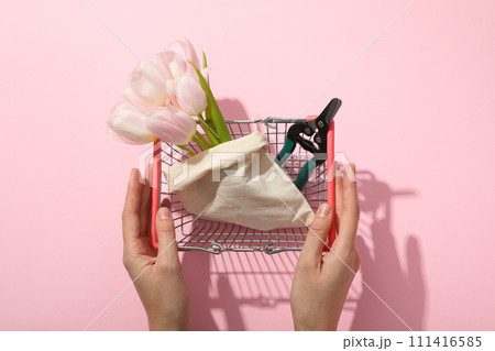 Secateurs, flowers in bag in shopping basket and hands on pink background, top view 111416585