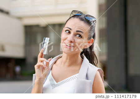 Happy successful business woman standing on city street, thinking about 111417179