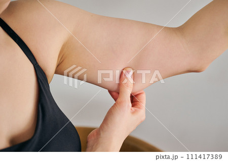 二の腕をつまんでたるみを確認する30代女性 二の腕をつまんでたるみを確認する30代女性 111417389