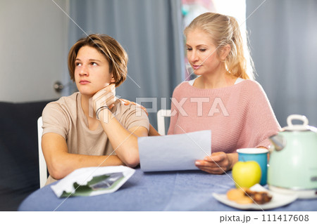 Unhappy mother and son reading letter from school Unhappy mother and son reading letter from school 111417608