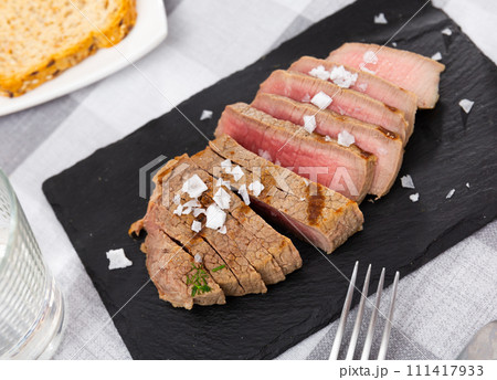 Fried veal steak served on black service board on the table 111417933