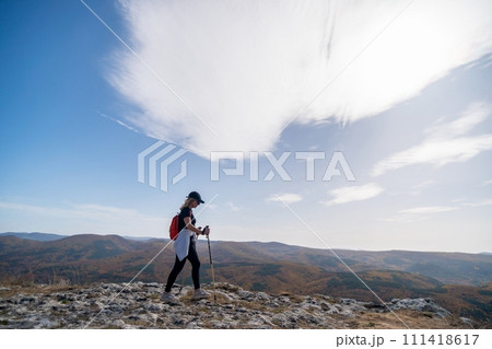 woman on mountain peak looking in beautiful mountain valley in autumn. Landscape with sporty young woman, blu sky in fall. Hiking. Nature 111418617
