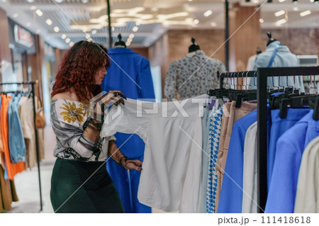 Shopping woman, women's fashion clothes in a store, boutique. Woman choosing clothes in a store 111418618