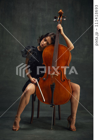 Elegant beautiful woman, cellist in moment of calmness sitting with eyes closed, connecting deeply with the music. Deep enjoyment of sounds 111418693