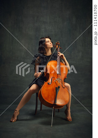 Beautiful woman, cellist looking upward, reflecting creativity and inspiration while playing. Promotion of live classical music event. 111418700