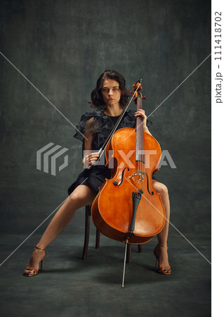 Female celloist sitting with cello on dark green background. Book cover for musician's memoir, emphasizing personal and artistic growth. 111418702