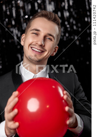 caucasian man in black jacket with red air balloon on dark glitter background. new year party 111420742