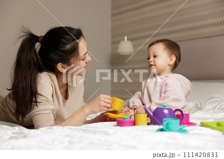 beautiful mother and little child daughter playing tea party in bedroom 111420831