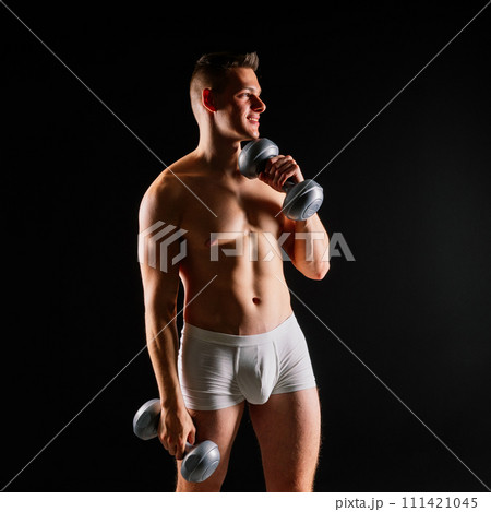 Shirtless bodybuilder holding dumbell and showing his muscular arms. Shirtless bodybuilder holding dumbell and showing his muscular arms. 111421045