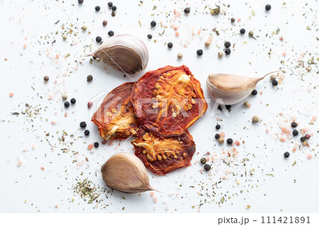 Dried tomatoes with black pepper and garlic on a white background. 111421891