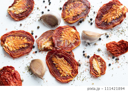Dried tomatoes with black pepper and garlic on a white background. 111421894