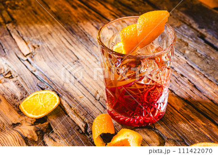 Delicious old fashion cocktail in the etched glass with ice and orange slices, dark wooden background. Shallow dof 111422070