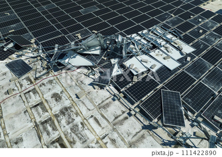 Aerial view of damaged by hurricane wind photovoltaic solar panels mounted on industrial building roof for producing green ecological electricity. Consequences of natural disaster Aerial view of damaged by hurricane wind photovoltaic solar panels mounted on industrial building roof for producing green ecological electricity. Consequences of natural disaster 111422890