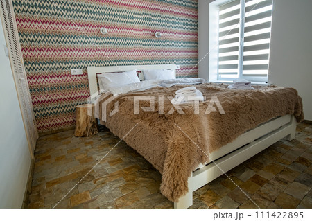 Interior of a spacious hotel bedroom with fresh linen on a big double bed. Cozy contemporary room in a modern house. 111422895