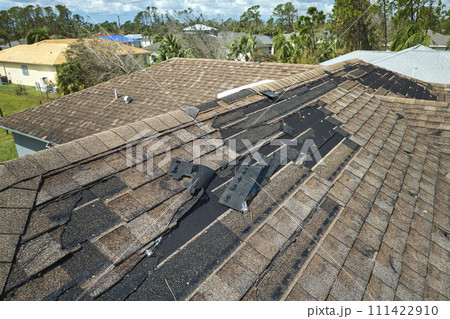 Wind damaged house roof with missing asphalt shingles after hurricane Idalia in Florida. Repair of home rooftop concept 111422910