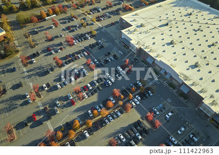 View from above of american grocery store with many parked cars on parking lot with lines and markings for parking places and directions. Place for vehicles in front of a strip mall center 111422963