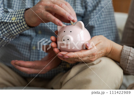 Saving money investment for future. Senior adult mature couple hands putting money coin in piggy bank. Old man woman counting saving money planning retirement budget. Saving investment banking concept Saving money investment for future. Senior adult mature couple hands putting money coin in piggy bank. Old man woman counting saving money planning retirement budget. Saving investment banking concept 111422989